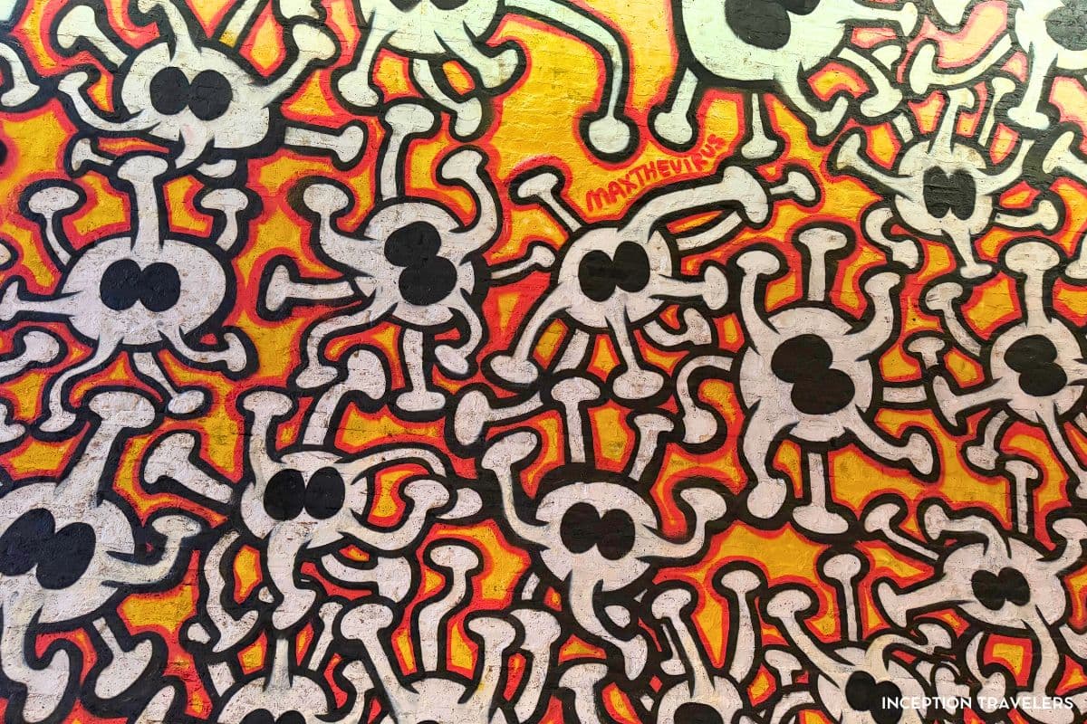 Wall of interlocking white cartoon virus characters on a red and yellow background in Leake Street