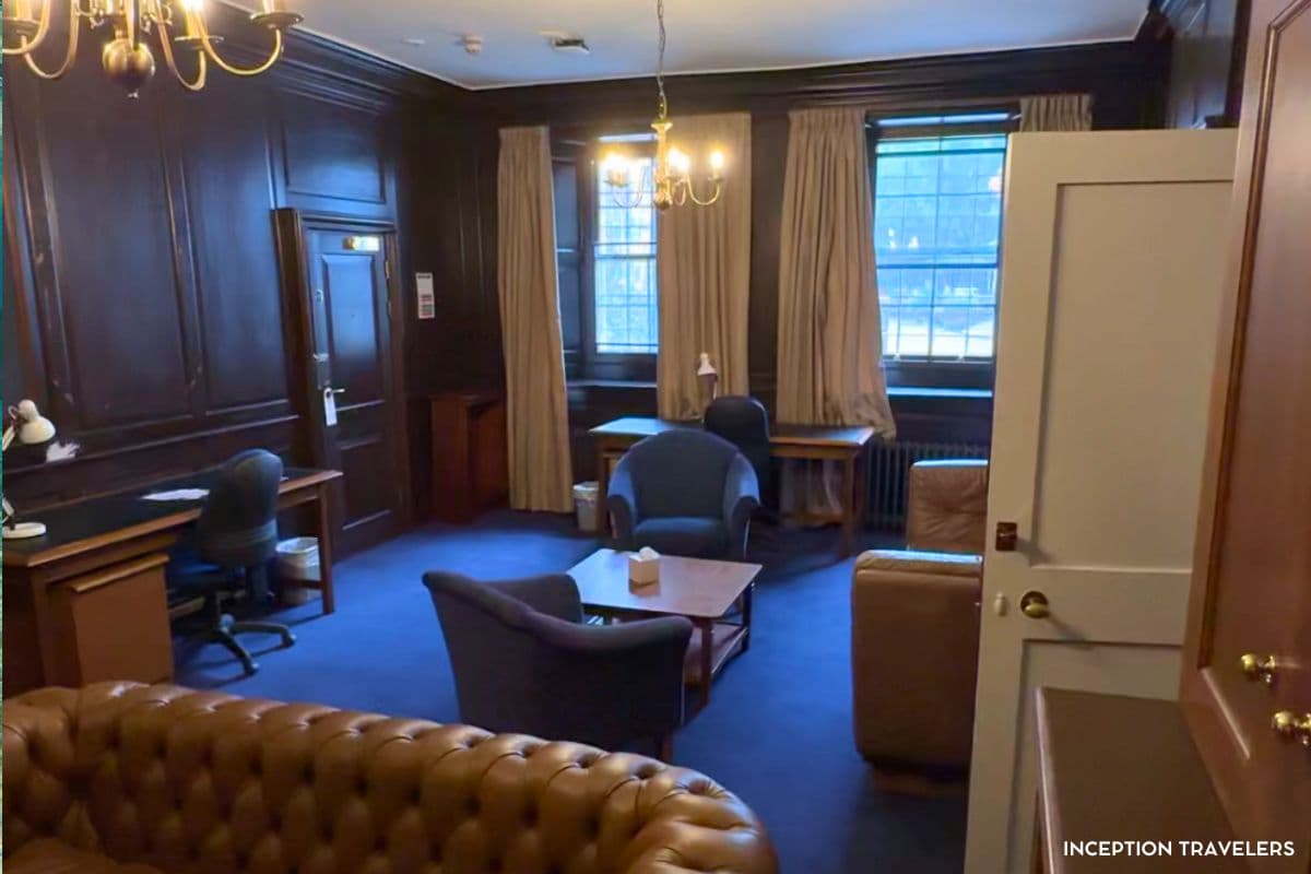 Dark wood-panelled guest room at Christ Church with writing desks, armchairs and a leather Chesterfield sofa