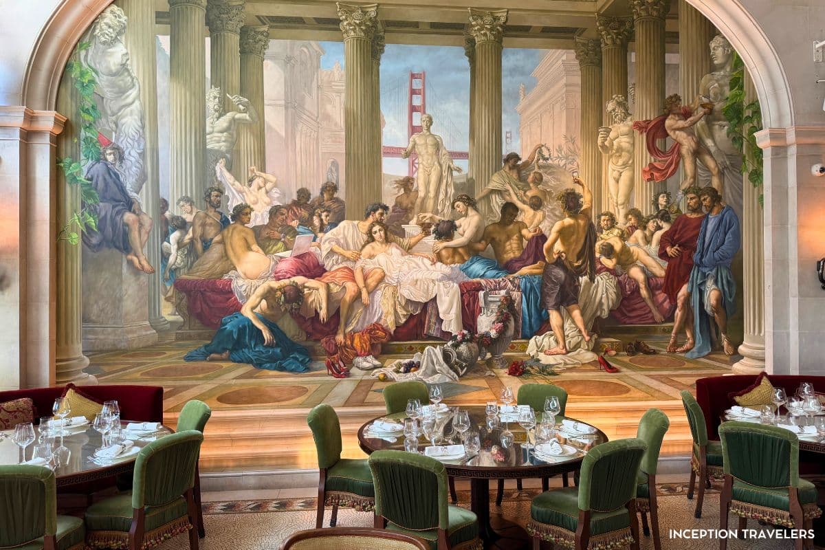 Floor-to-ceiling Roman feast mural, Golden Gate Bridge painted into the scene, behind green velvet dining chairs