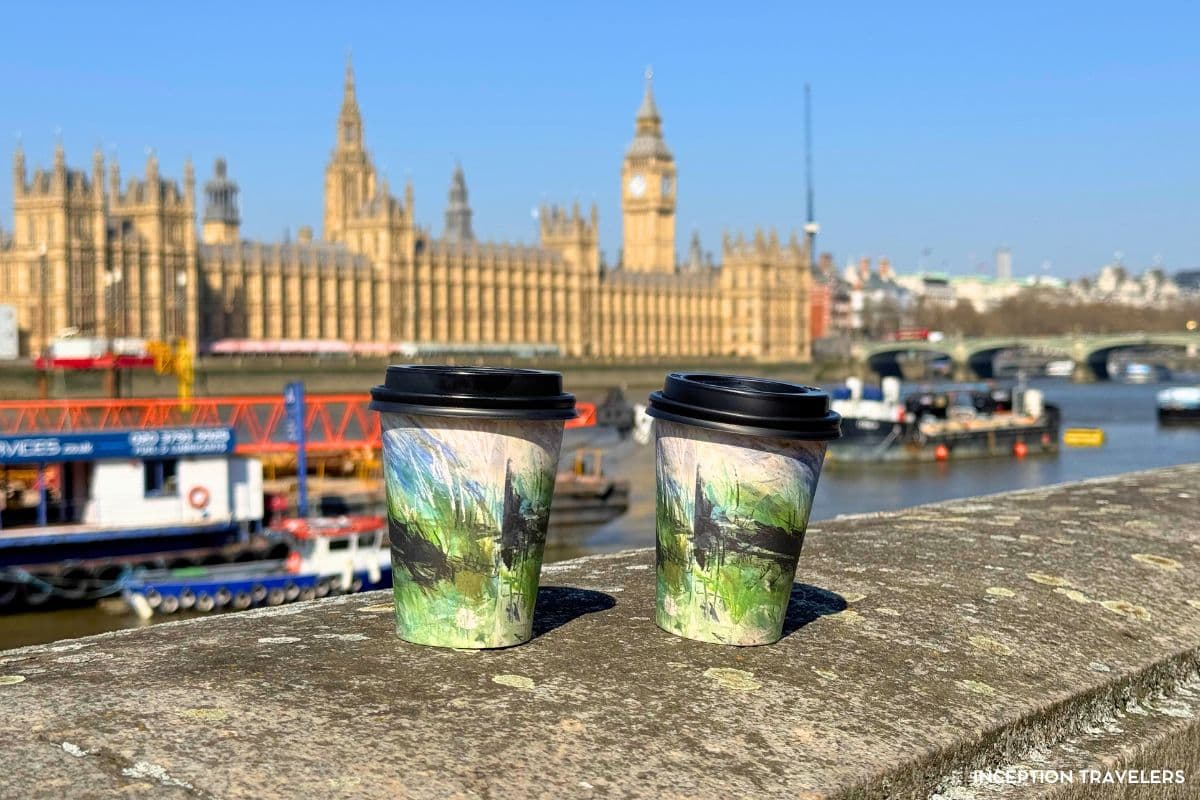 Two painted takeaway cups on the embankment wall, the Houses of Parliament soft-focused across the Thames