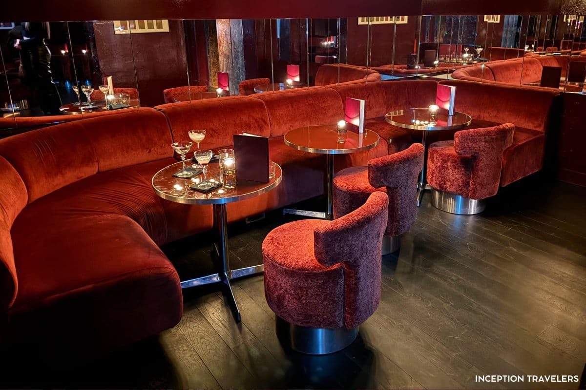Red velvet banquettes and swivel stools around candlelit cocktail tables in Bar Lina's mirrored lounge