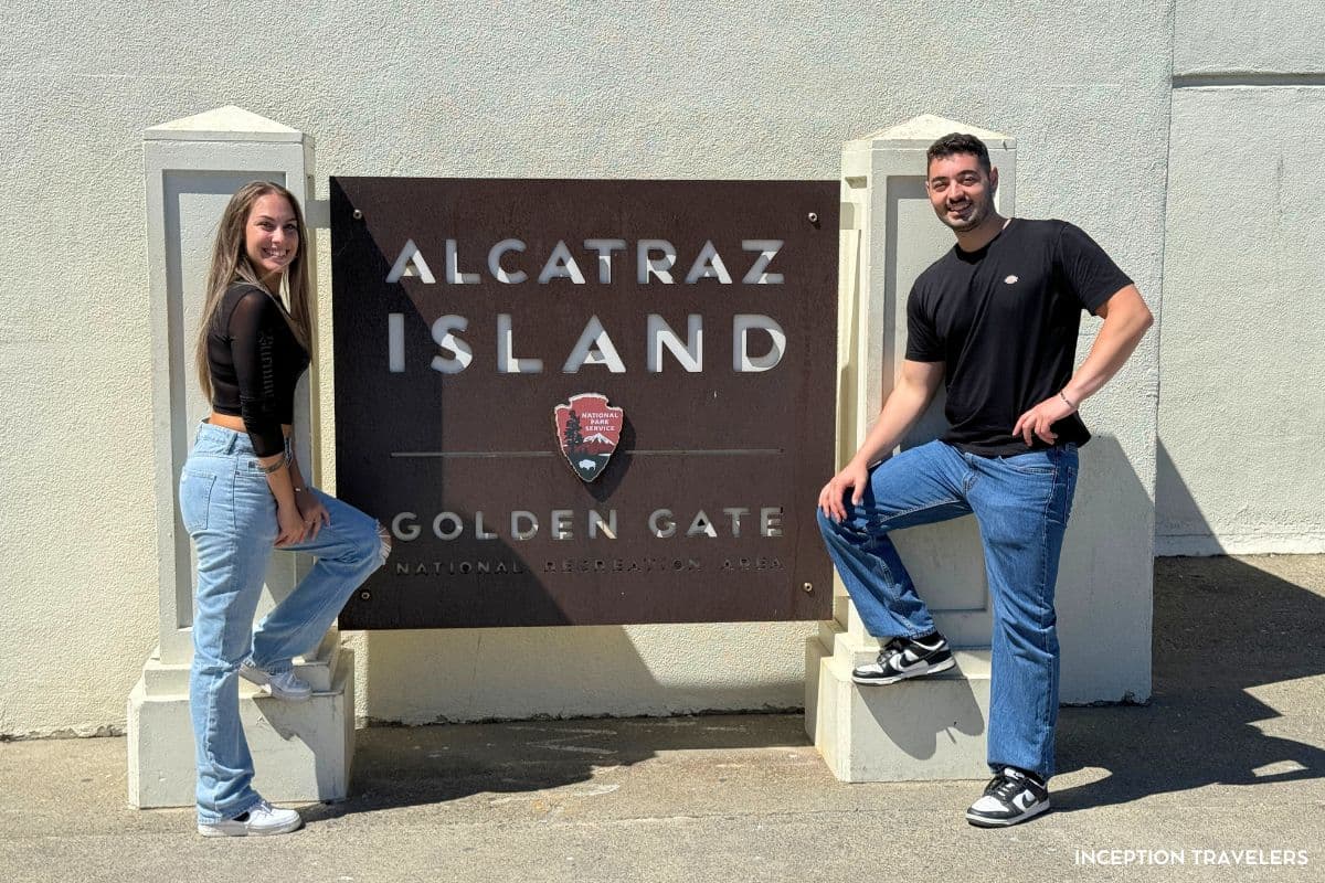 Two visitors posing beside the Alcatraz Island sign of the Golden Gate National Recreation Area