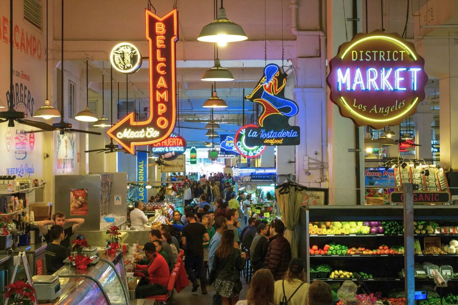 Neon vendor signs glowing over the crowded food aisles of Grand Central Market