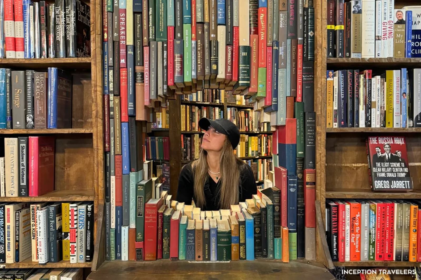Woman looking up through a window formed of hanging books inside The Last Bookstore