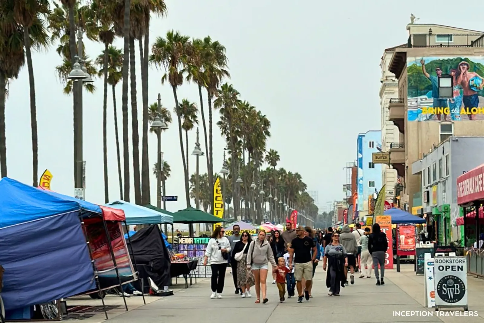 Vendor canopies and towering palms lining the busy Venice Beach boardwalk