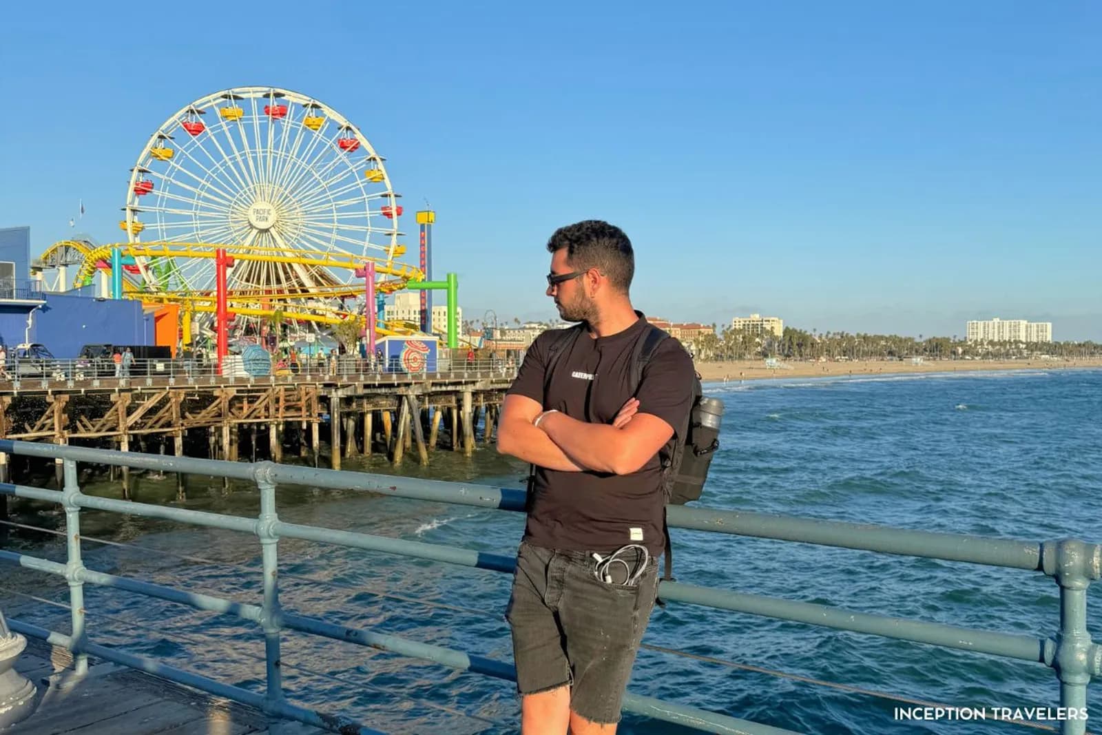 Man on Santa Monica Pier with the Pacific Park Ferris wheel and roller coaster behind