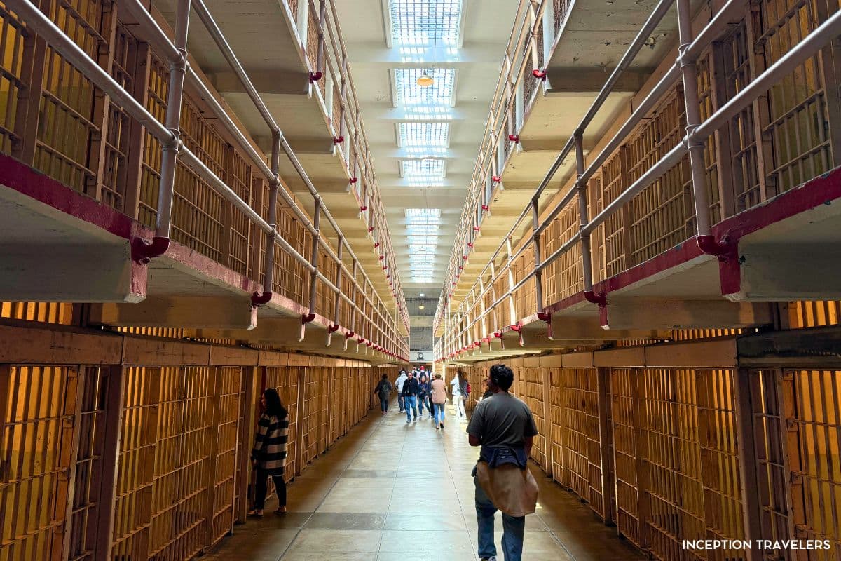 Broadway cell block inside Alcatraz, three tiers of barred cells with visitors walking beneath the skylights