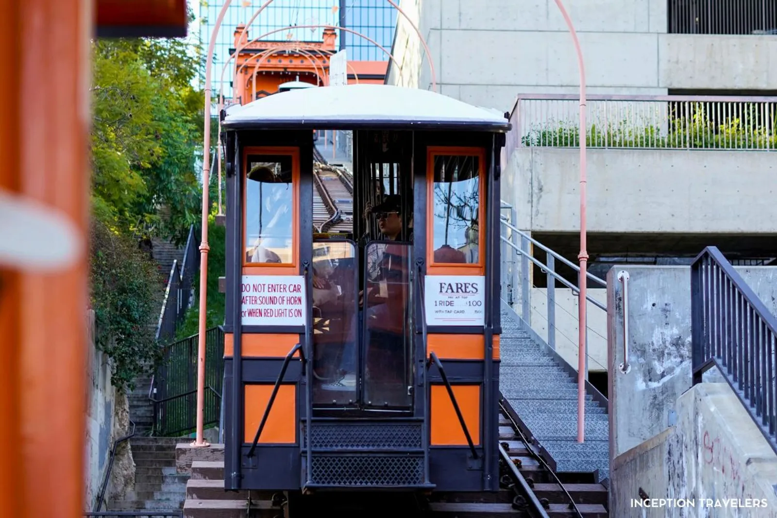 Orange Angels Flight funicular car climbing its track beside a staircase in downtown Los Angeles