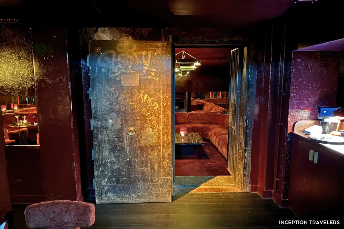 Graffiti-etched vault door opening onto Bar Lina's hidden red velvet lounge